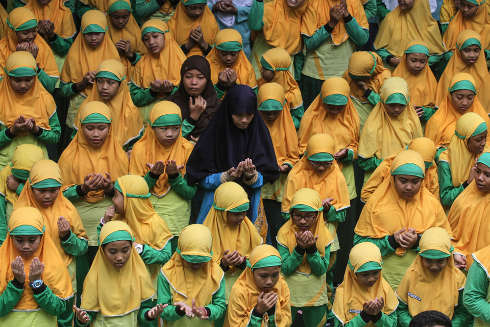 Trust God: A group of elementary school students pray together at a solidarity event in Surakarta, Central Java, to honor those affected by the Aceh earthquake.